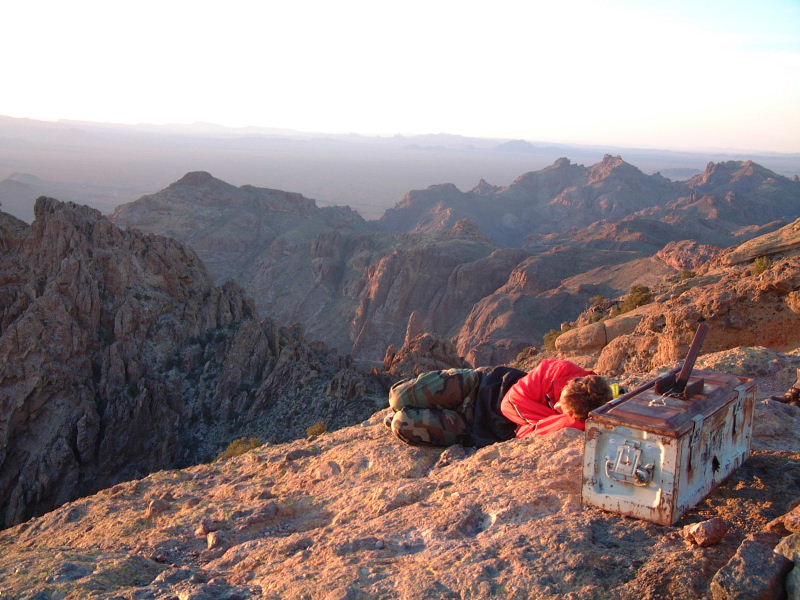 Jeff curls up on the windy peak of Mount Ajo awaiting sunset.