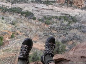 Uncrazy me sitting on the cliff thinking it's a long drop while waiting for Crazy Steve to crawl back across a narrow ledge from the apparently defensive walls of the upper level of Jailhouse Ruin in Bullet Canyon.